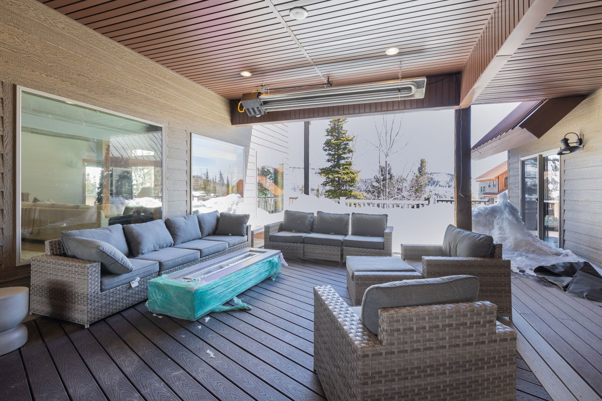 Covered outdoor living area featuring a wood-slat ceiling, recessed lighting, and a wall-mounted outdoor heater