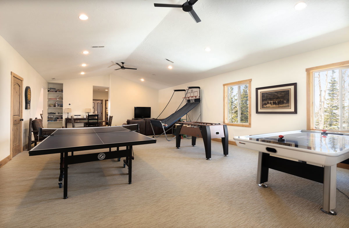 Spacious recreation room featuring recessed lighting, a vaulted ceiling, and two ceiling fans