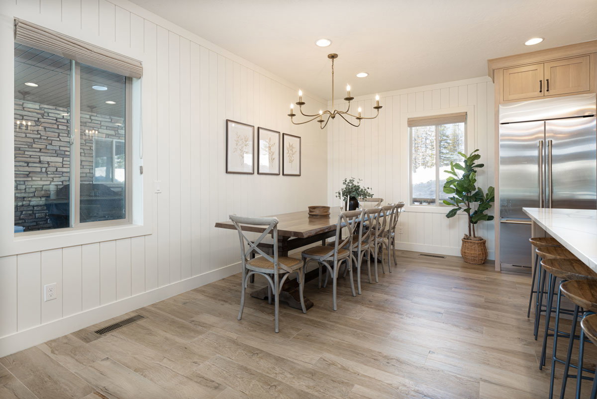 Dining area featuring plank-style wood-finish flooring, white shiplap wall paneling, a bronze chandelier, recessed lighting, and a window with a roller shade