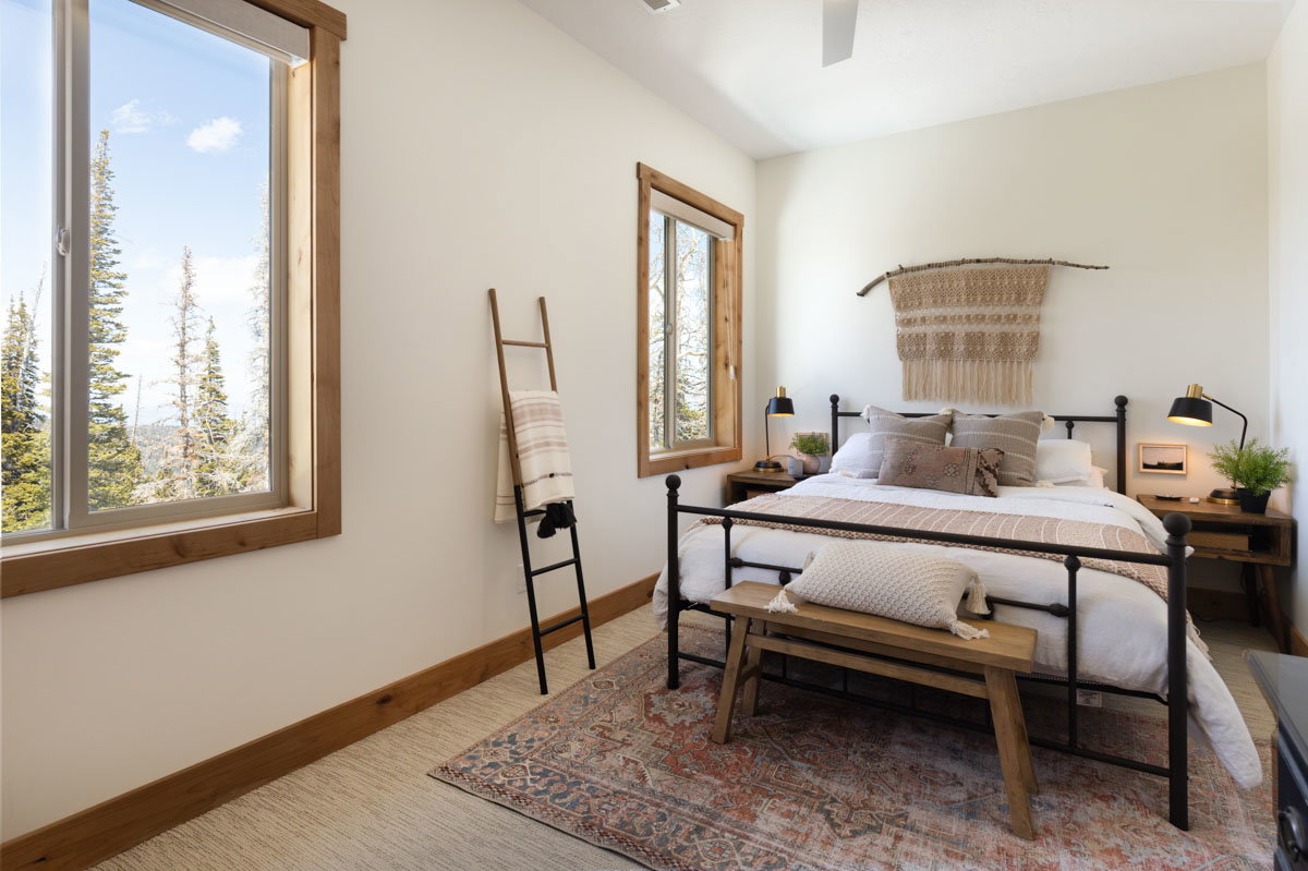 Bright bedroom featuring a large picture window with a natural wood frame, a ceiling fan, and carpeted flooring