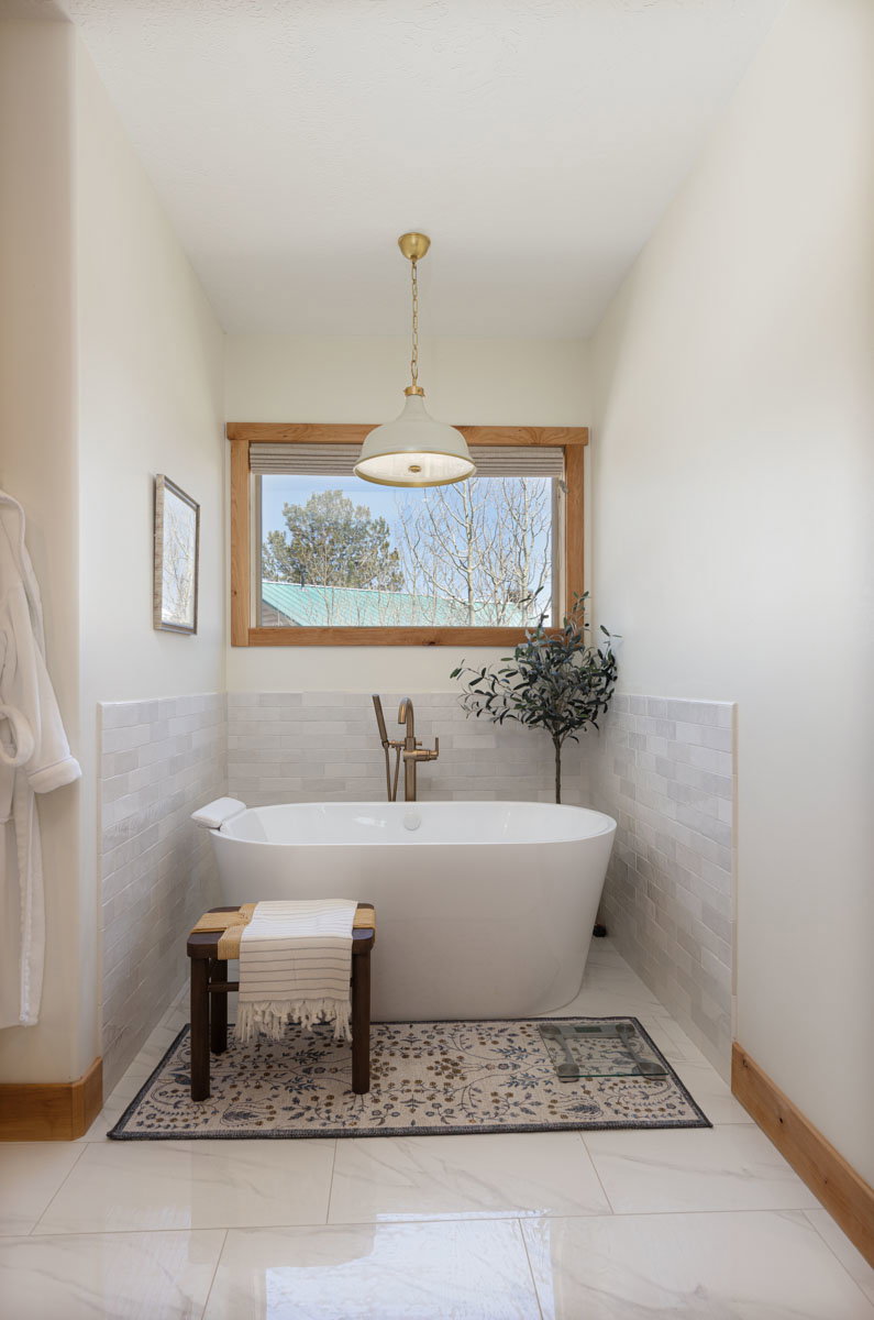 Freestanding white soaking tub with a wall-mounted brass faucet