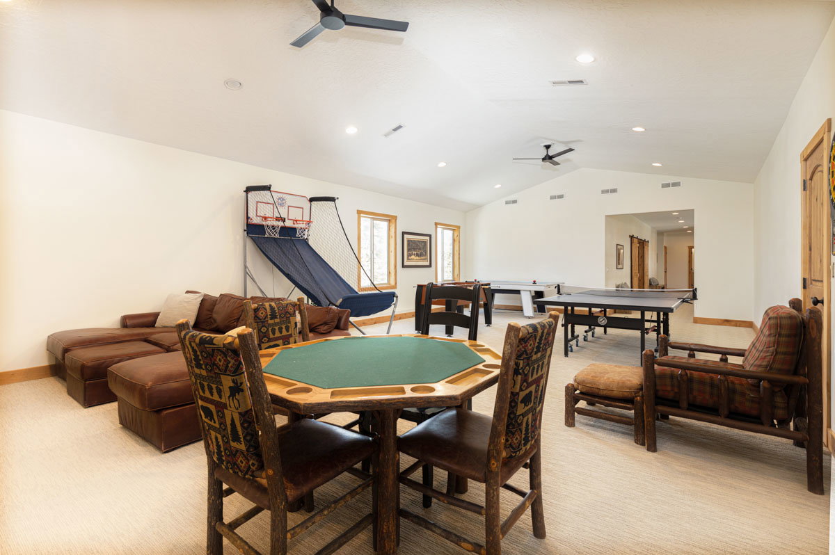 Spacious room featuring vaulted ceilings, recessed lighting, two ceiling fans, and light-toned carpeting