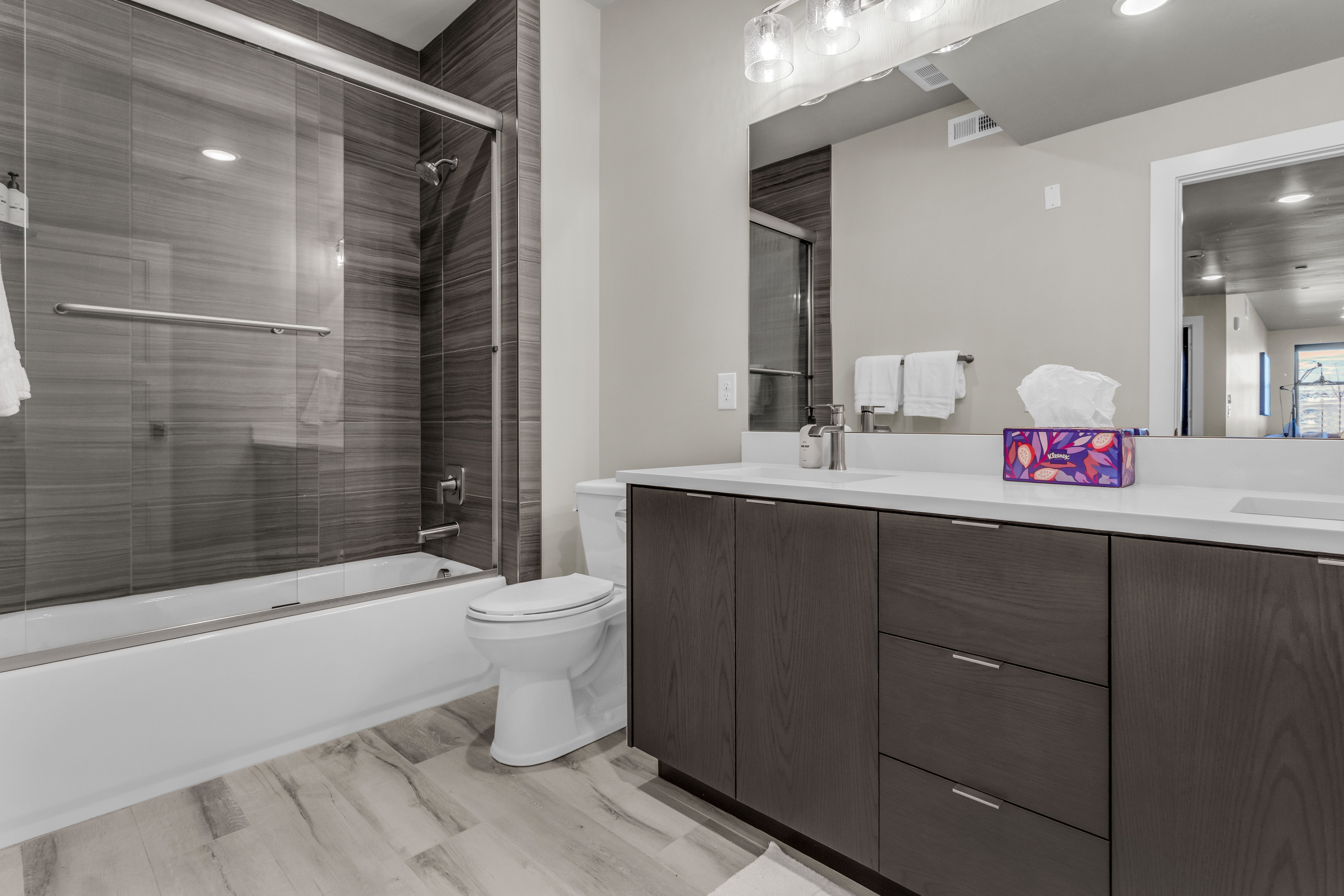 Dual vanity with white countertops, dark wood-finish cabinetry, and contemporary hardware