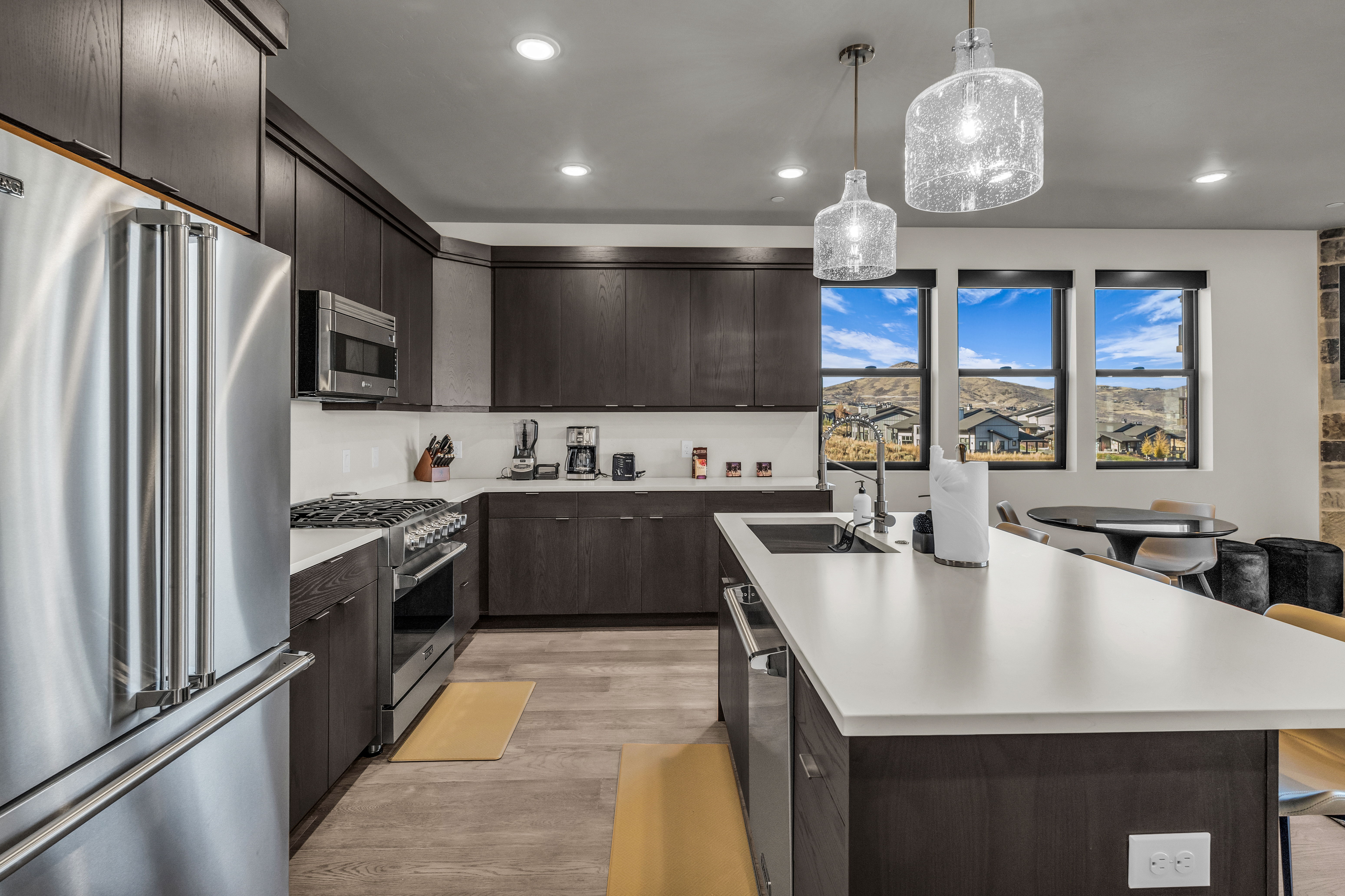 Contemporary kitchen featuring dark wood-finish cabinetry, white countertops, and stainless steel appliances