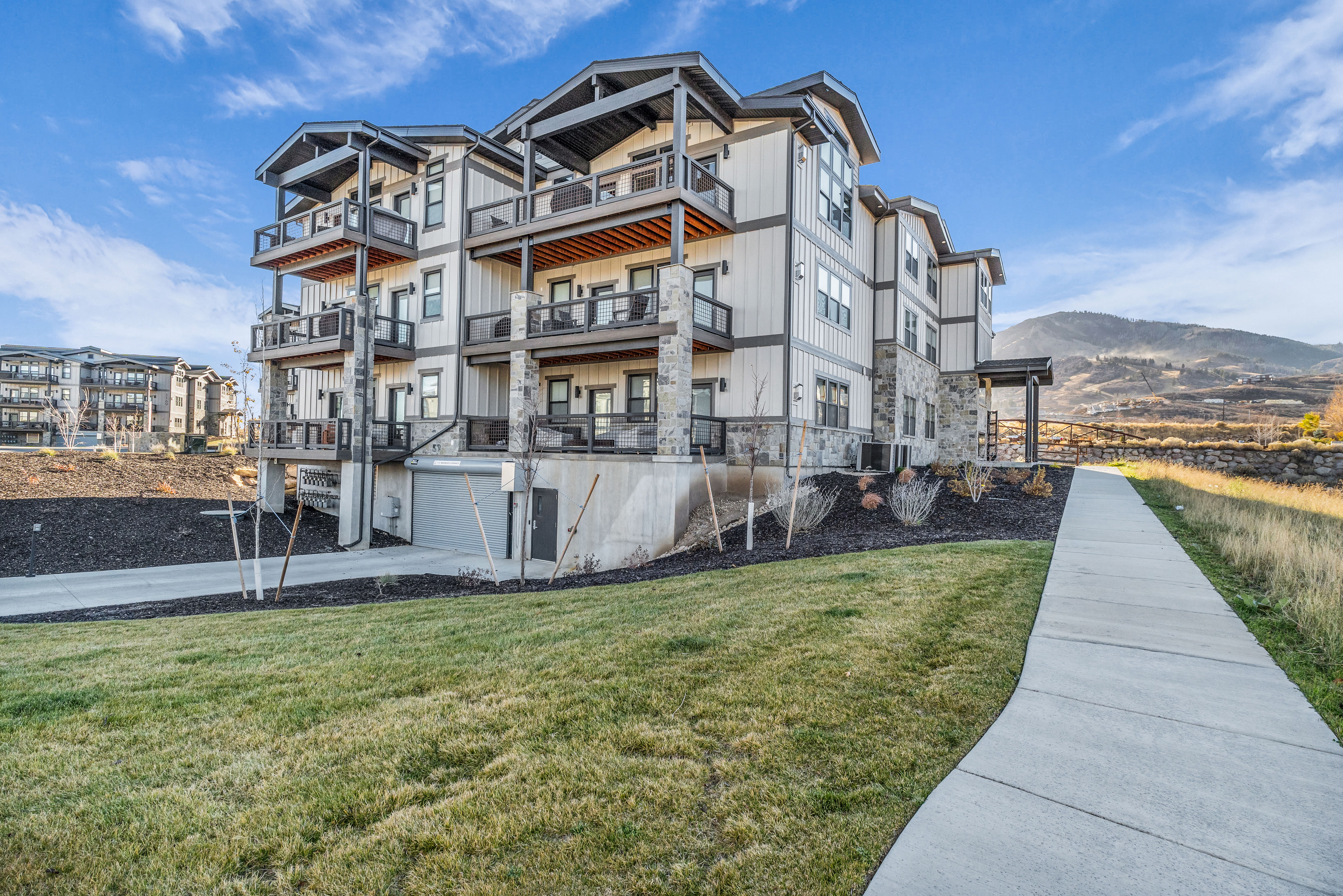 Multi-story residential building featuring a combination of light-colored siding and stone facade