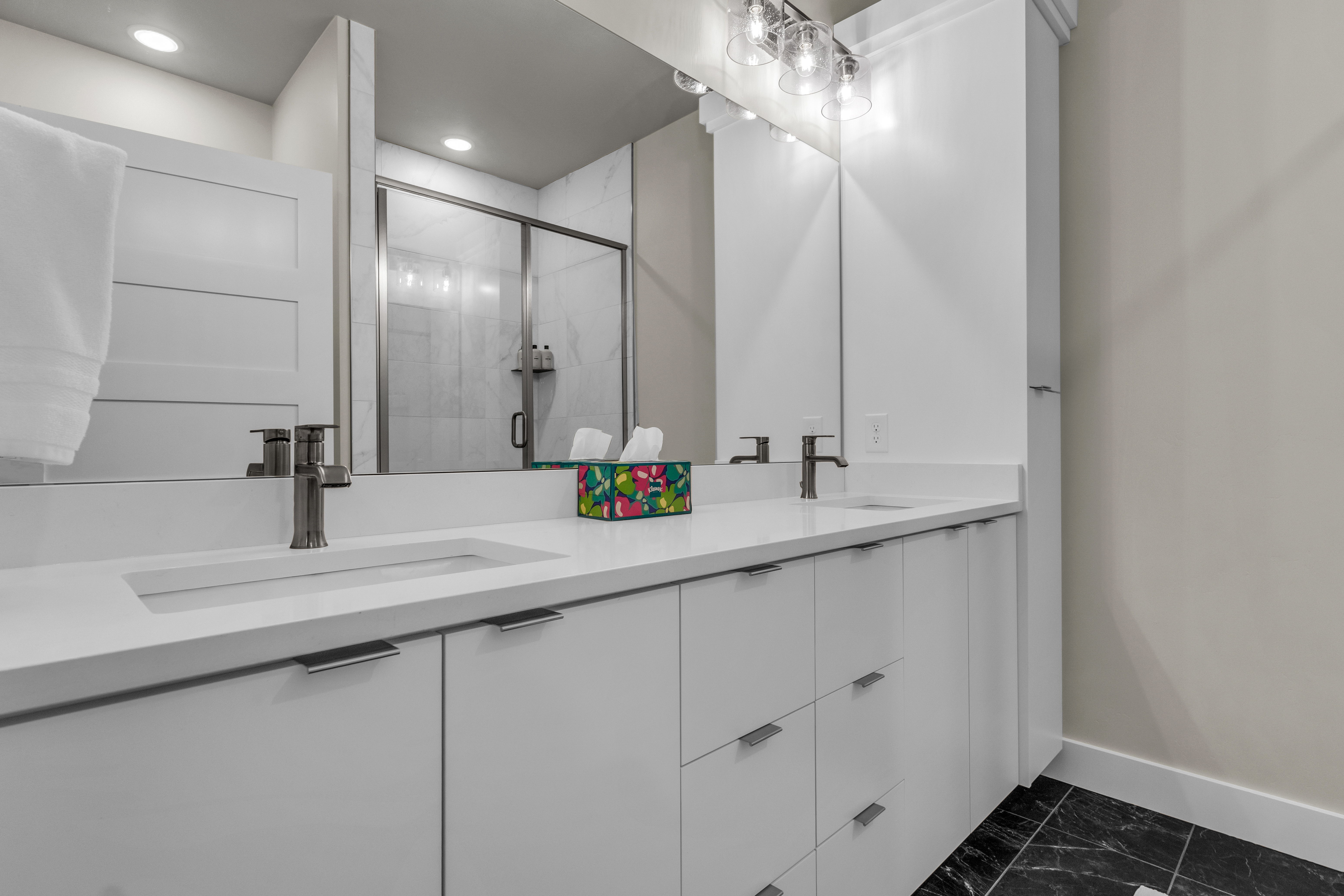 Double vanity with integrated sinks, white cabinetry, and brushed nickel hardware