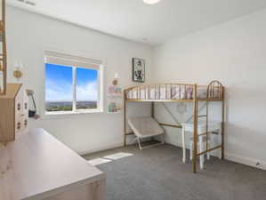 Bright room featuring a large window, neutral carpeting, and white walls