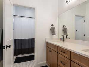 Double vanity featuring a light-toned countertop, wood-finish cabinetry, and matte black fixtures
