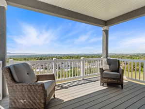 Covered outdoor deck featuring white railing, gray support columns, and composite decking