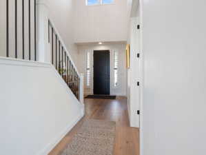 Two-story entryway with wood-finish flooring, a contemporary black door, and white walls