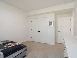 Bedroom featuring light beige carpet flooring, crisp white walls, and a recessed ceiling element