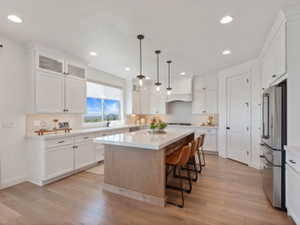 Expansive kitchen featuring white cabinetry, light wood-finish flooring, and recessed lighting
