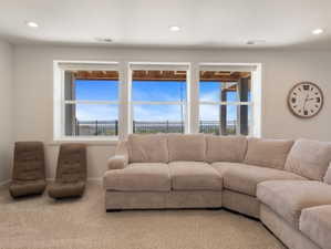 Bright living space featuring three large windows showcasing distant landscape, recessed lighting, and light-toned carpet flooring