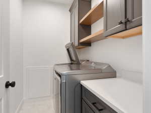 Laundry area with grey shaker-style cabinetry, open wood shelving, and a white countertop