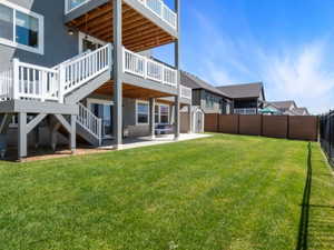 Expansive grassy lawn bordered by a black metal fence and a brown privacy fence