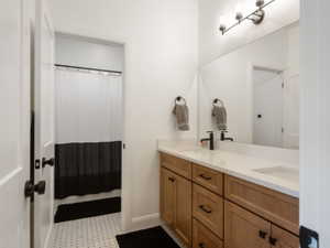 Double vanity with light wood-finish cabinetry, white countertops, and matte black fixtures