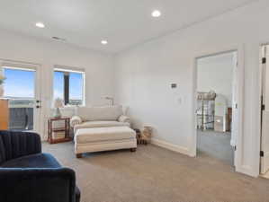 Carpeted room featuring a white door to an exterior balcony, a large window, recessed lighting, and white baseboards