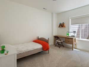 Carpeted room featuring a single window with a roller shade, white walls, and recessed lighting