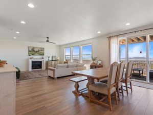 Open-concept living area with wood-finish flooring, recessed lighting, and a white fireplace with a mantel