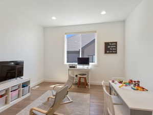 Bright room featuring wood-finish flooring, recessed lighting, white walls, and a large window