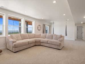 Expansive room with large windows, light-colored carpeting, recessed lighting, and white walls