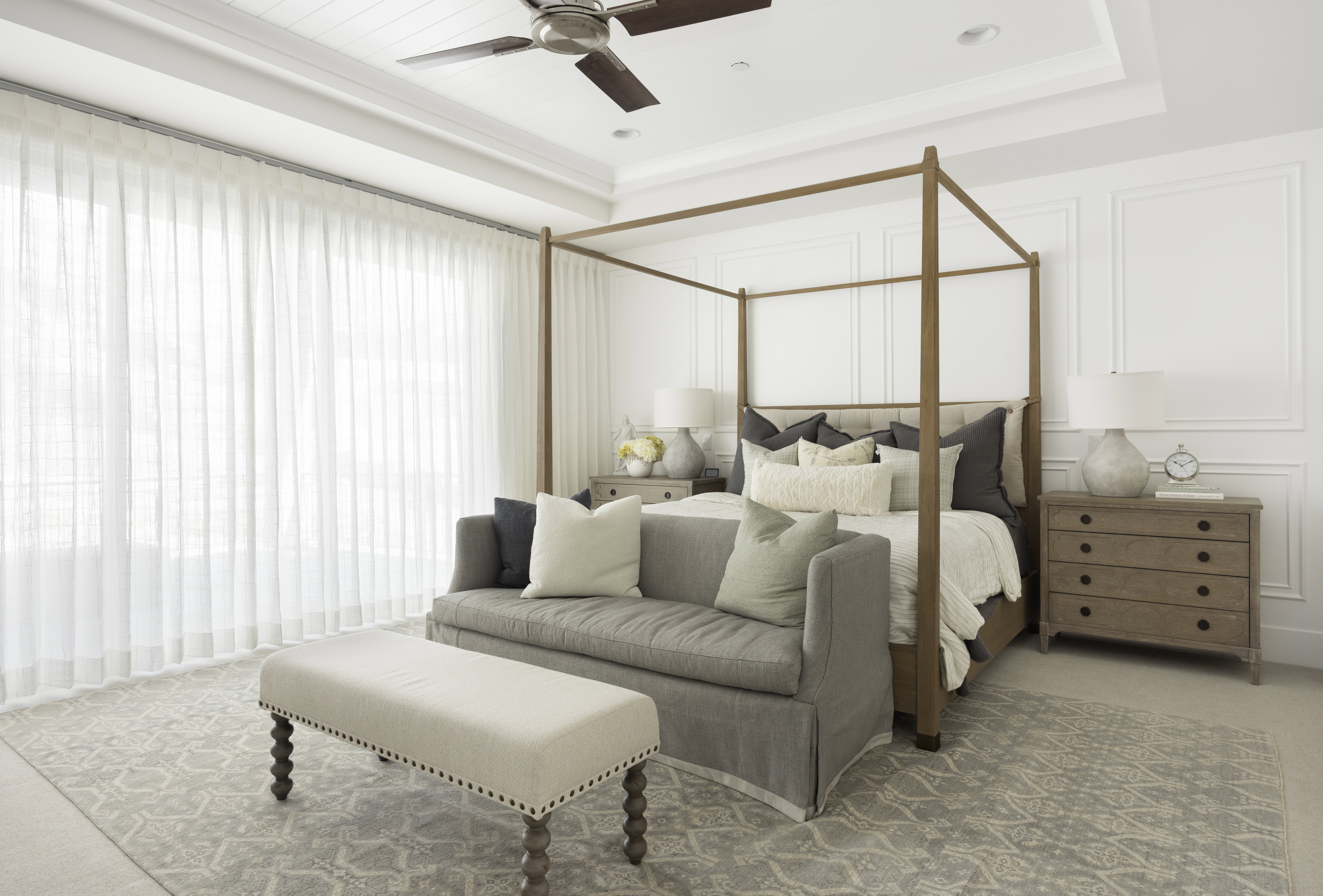 Spacious room featuring extensive wall paneling, a tray ceiling, and a ceiling fan