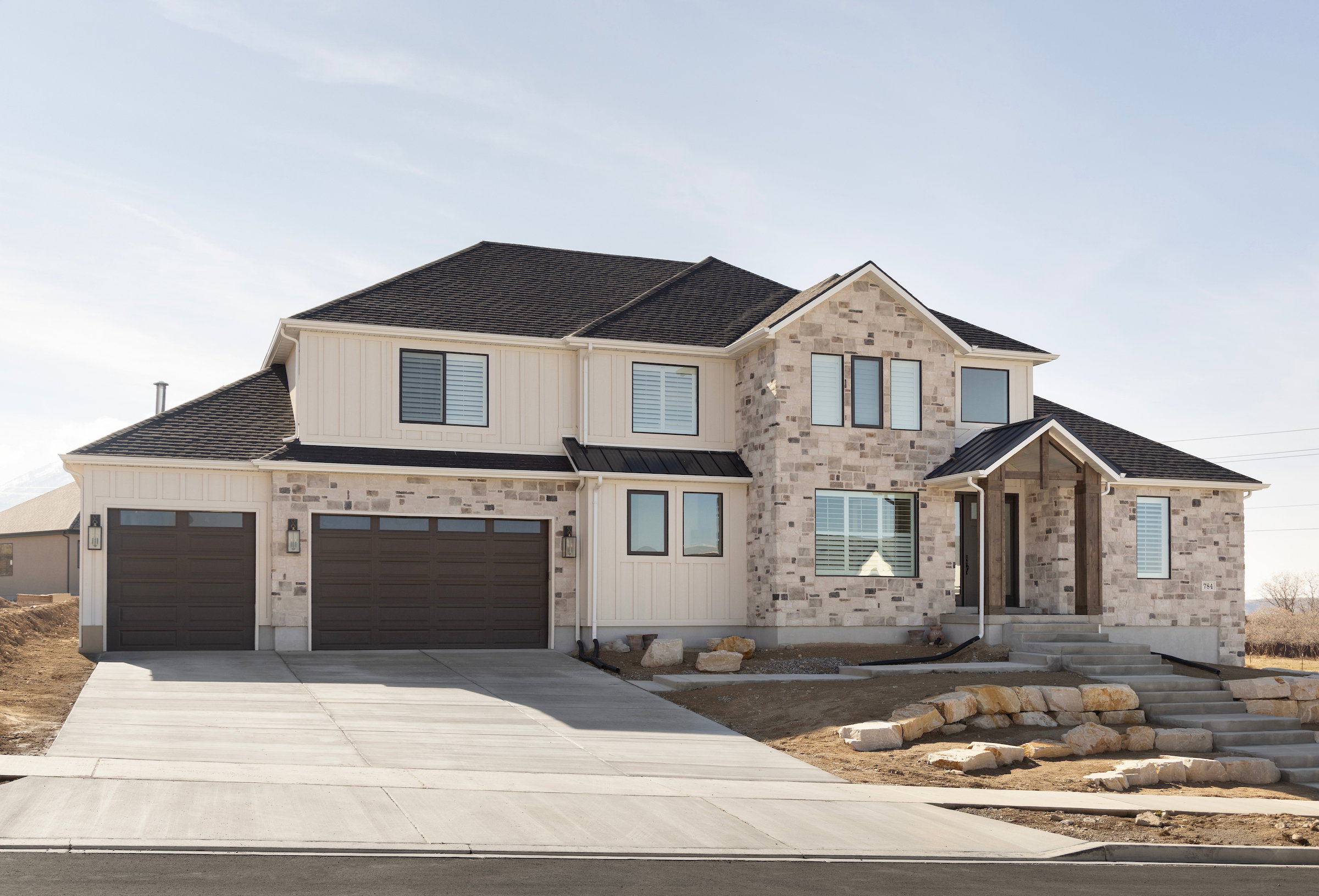 Contemporary two-story residence featuring a stone and vertical siding facade