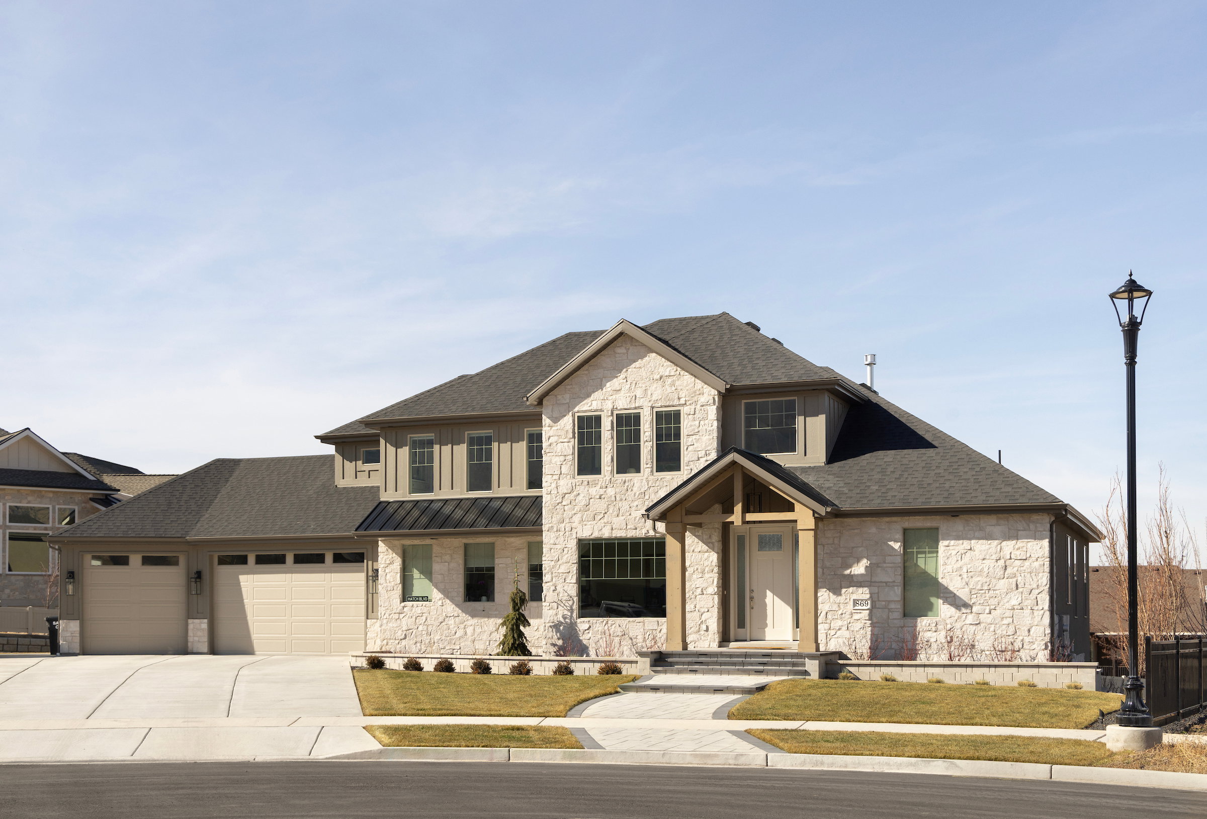 Stone veneer exterior with wood accents, a covered front entry, and a multi-car garage with overhead doors