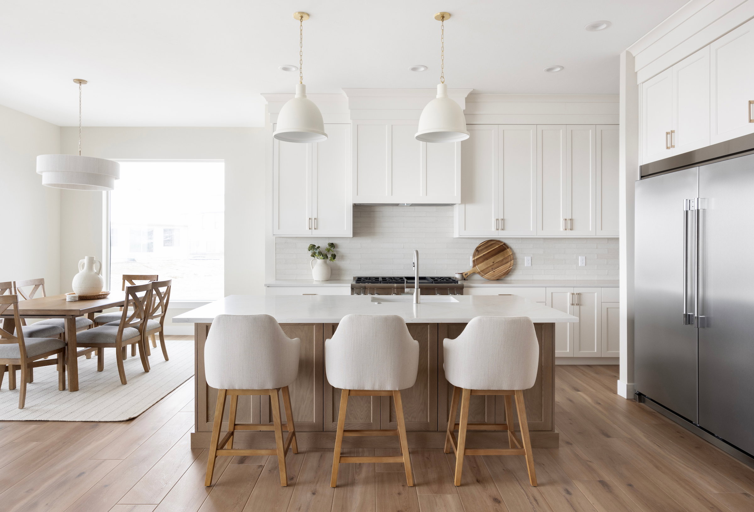 Gourmet kitchen featuring white shaker cabinetry, stainless steel appliances, and a central island with counter seating