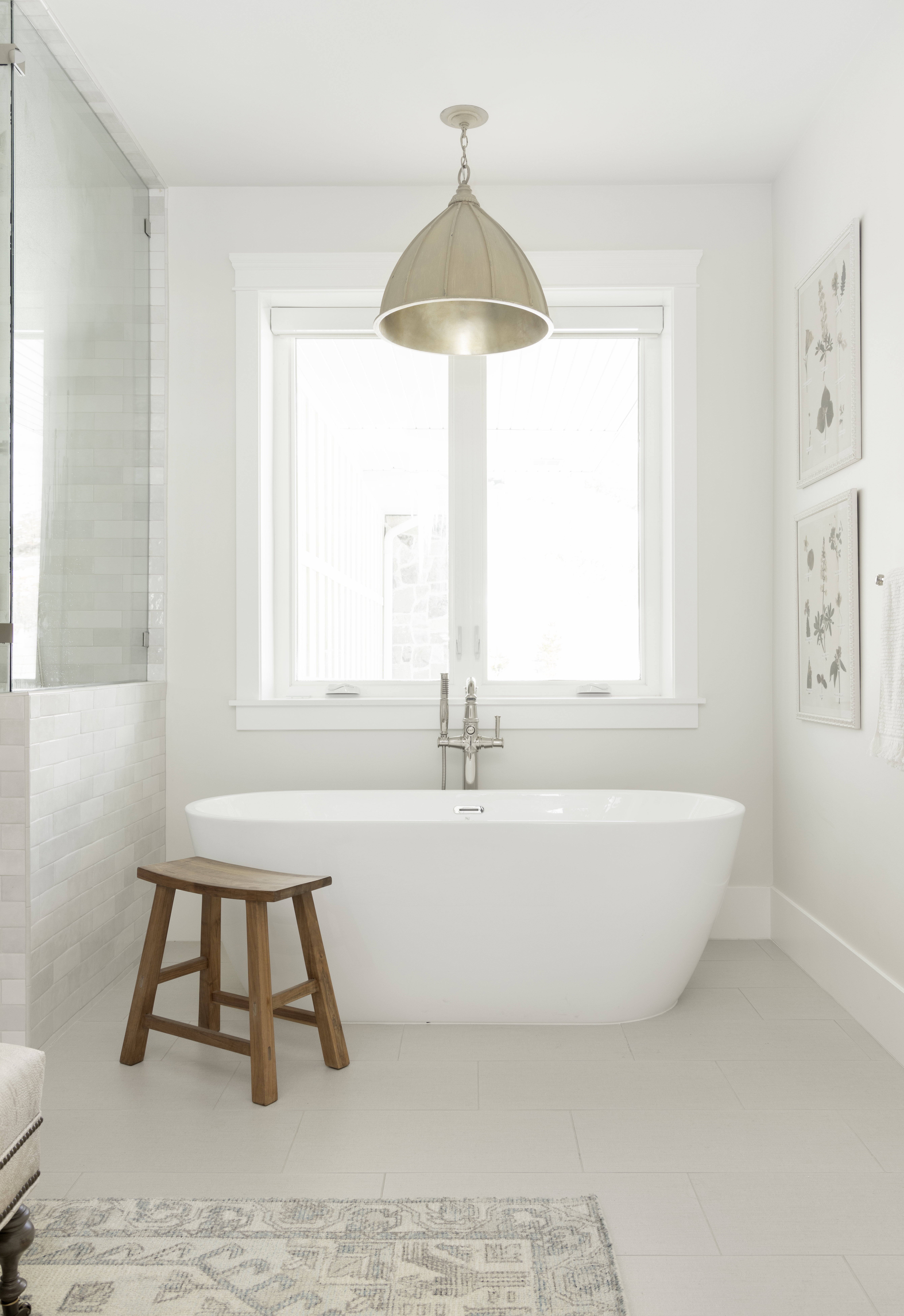 Freestanding soaking tub with brushed nickel floor-mounted faucet, set against a window with white trim
