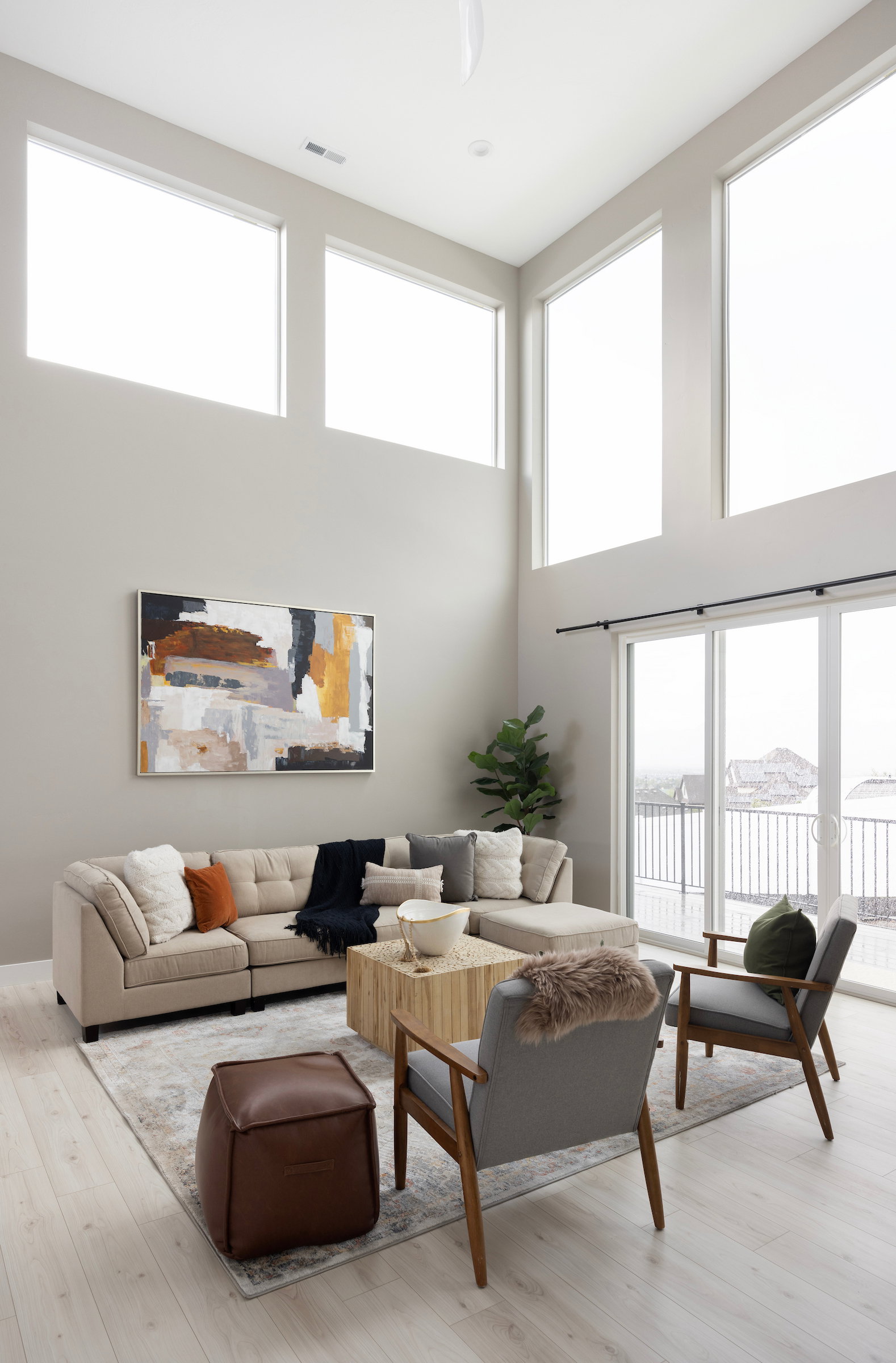 Two-story living area featuring high ceilings, upper-level transom windows, wood-finish flooring, and sliding glass doors
