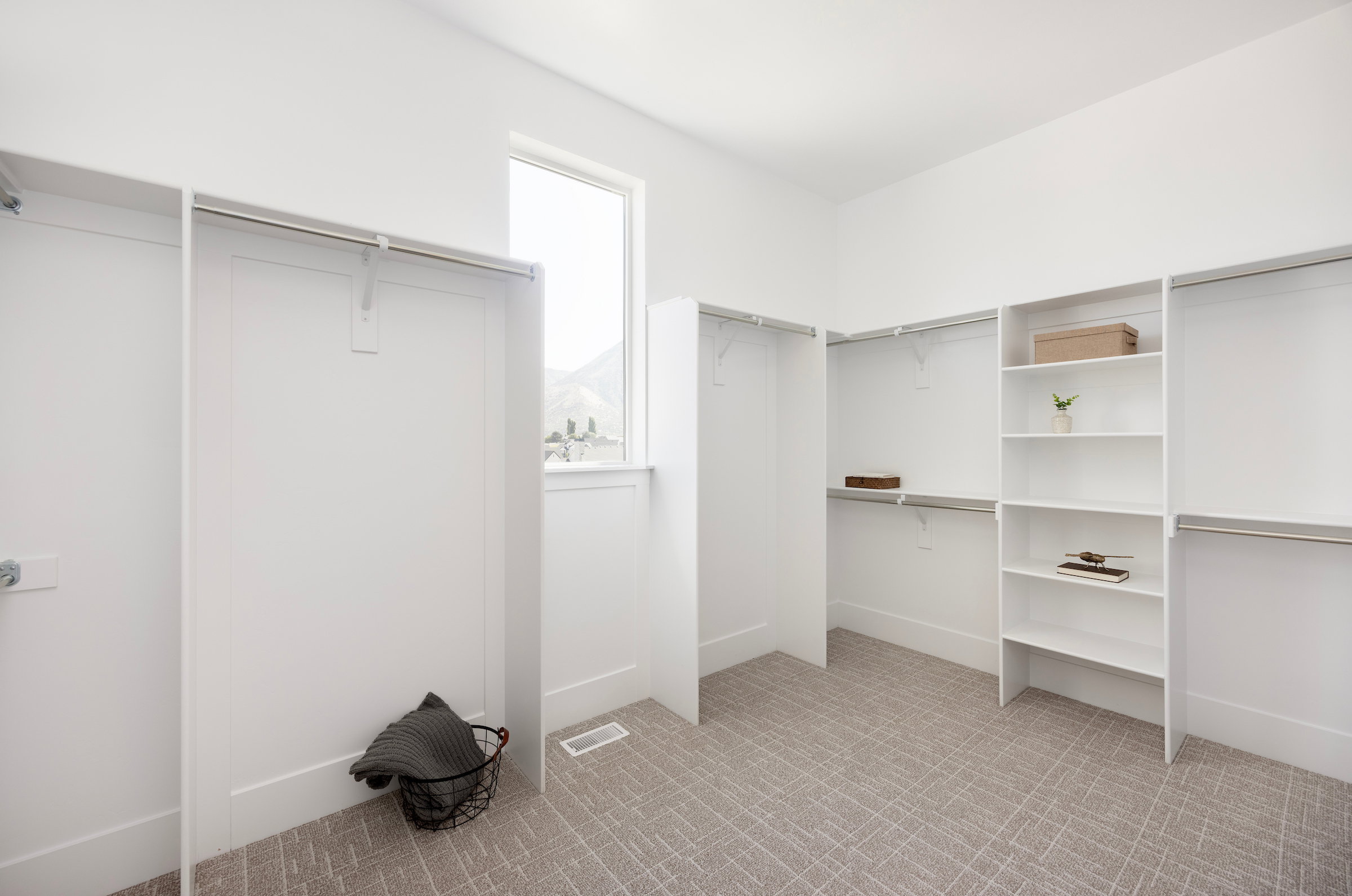 Spacious closet featuring built-in shelving, multiple hanging rods, and a large window