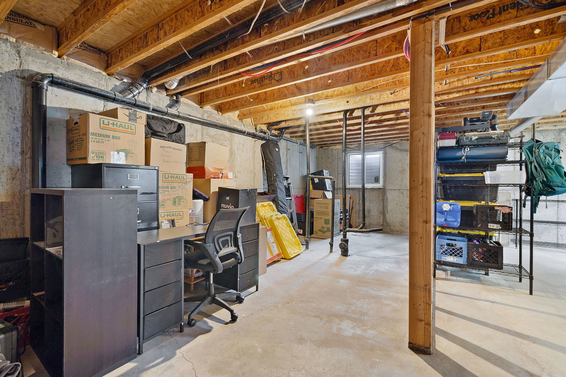Unfinished basement space featuring exposed wood joists, concrete foundation walls, and a concrete floor