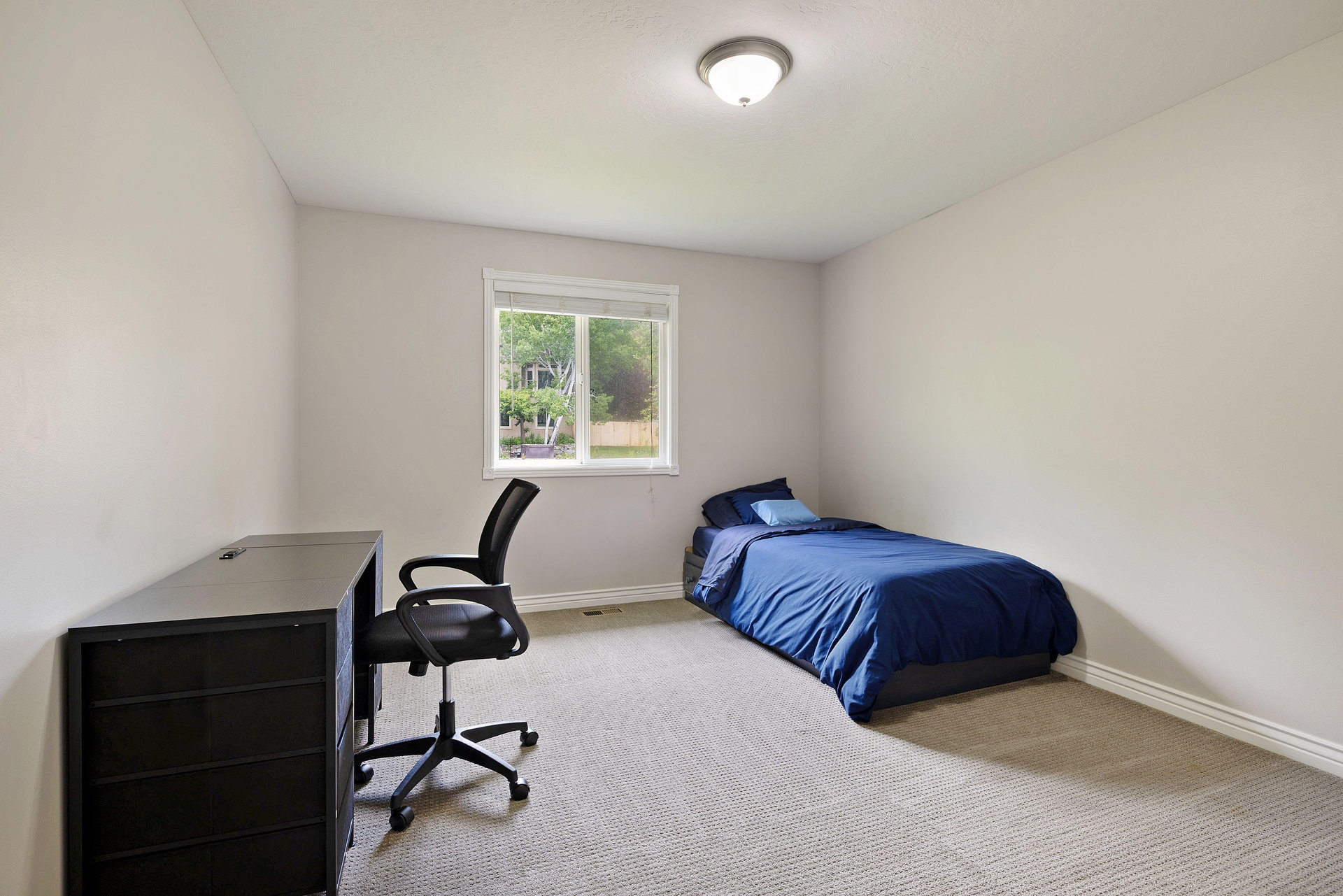 Bright room with a neutral color palette, featuring a window and carpeted flooring