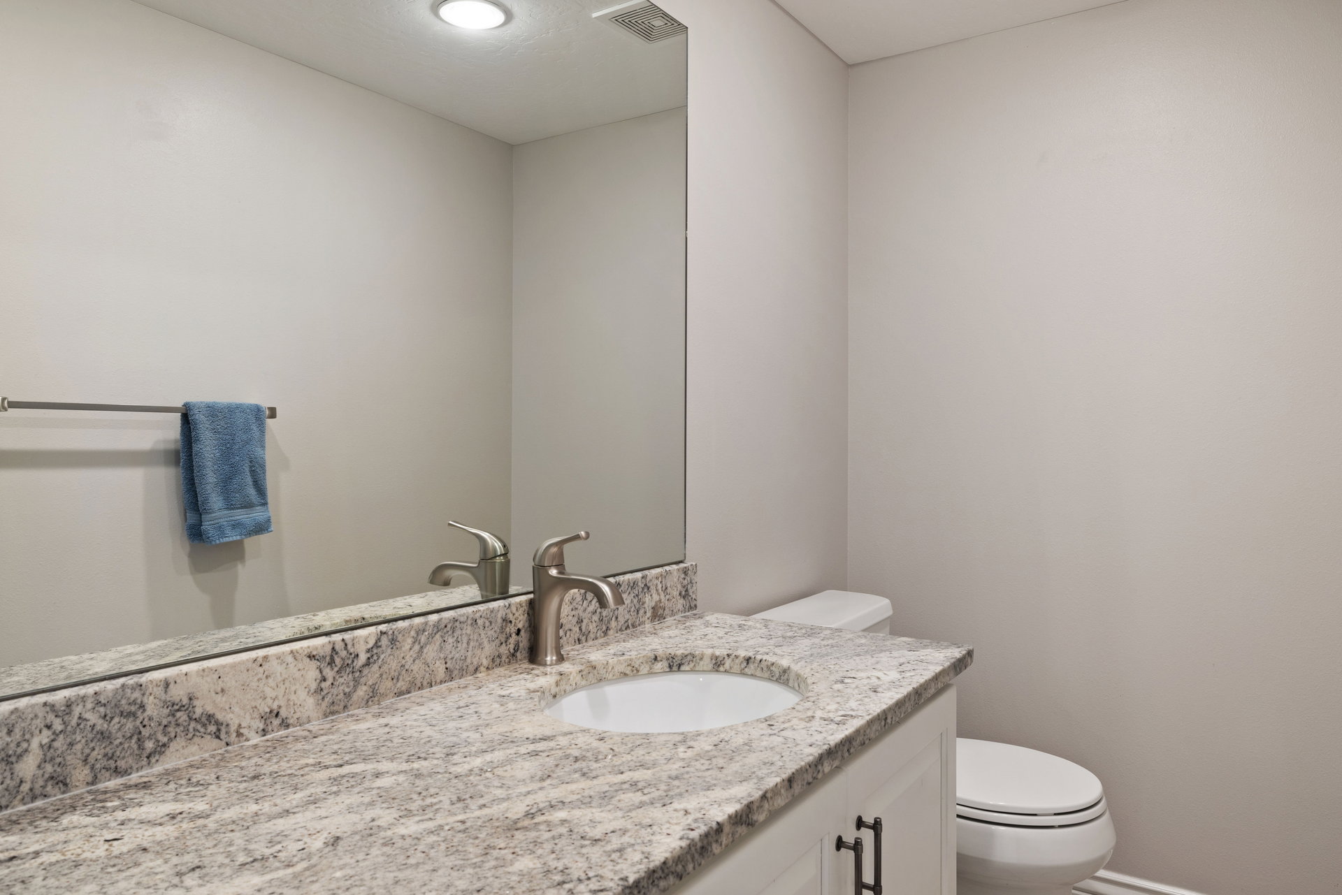 Bathroom featuring a white vanity with dark hardware, undermount sink, brushed nickel faucet, and a granite-finish countertop