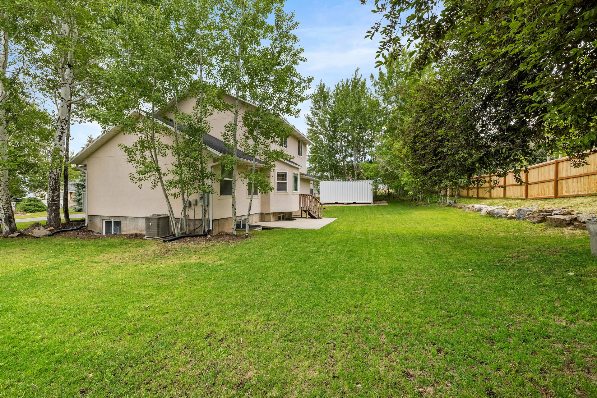 Expansive green lawn bordering a two-story residence with a light-colored stucco exterior