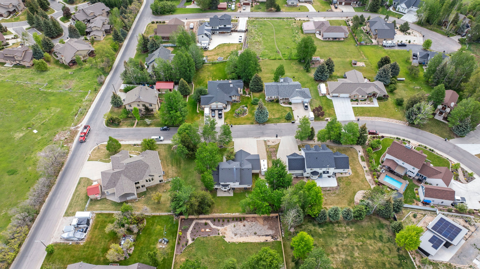 Aerial perspective showcasing a residential neighborhood with diverse architectural styles, mature trees, and ample green space