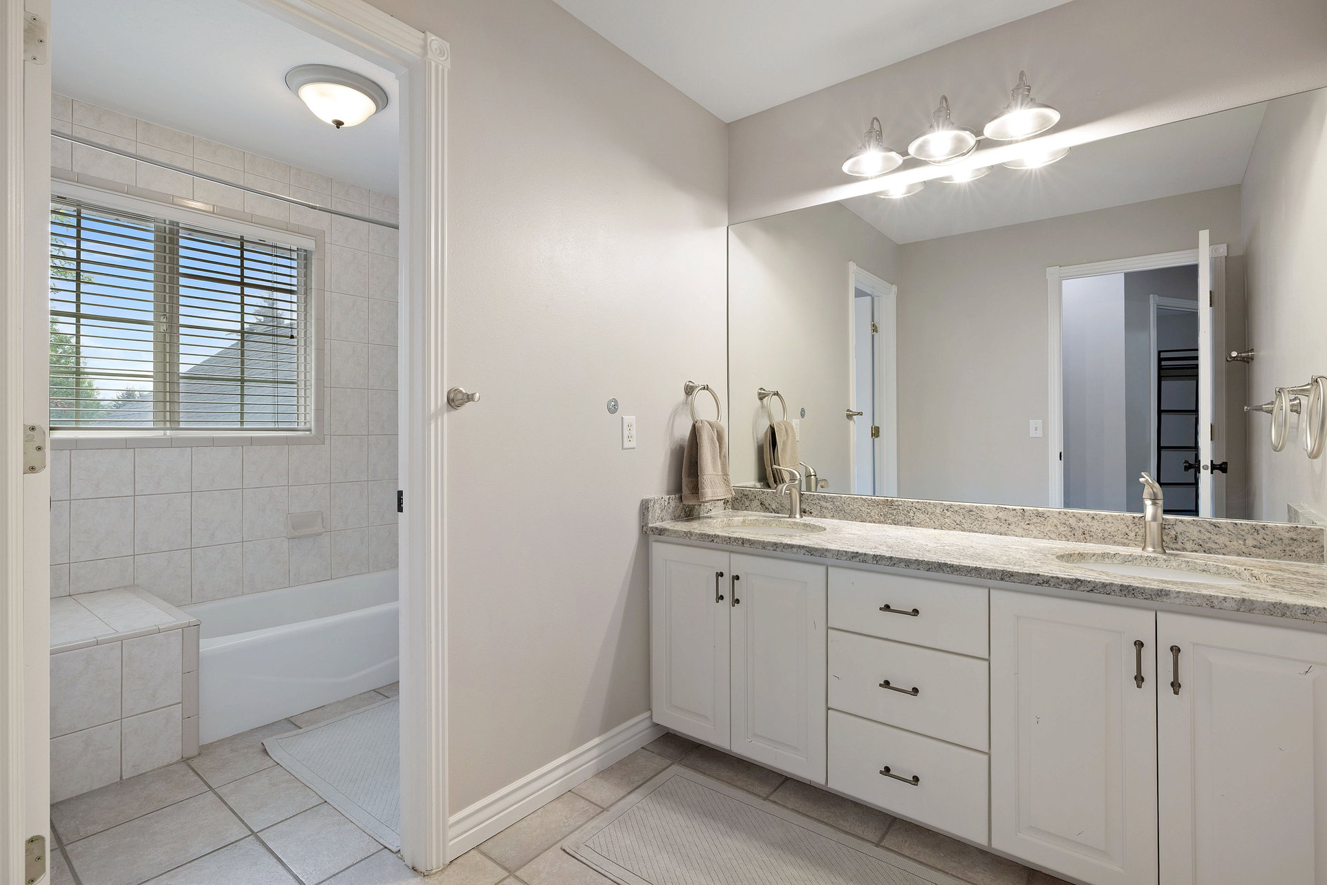 Dual vanity featuring white cabinetry, granite-finish countertop, and undermount sinks