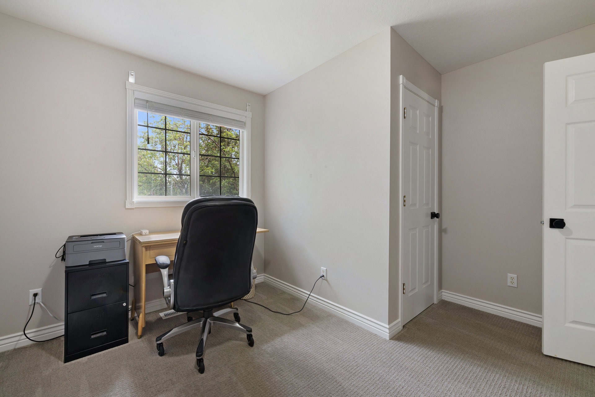 Carpeted room featuring a window with natural light, white trim, and two white panel doors with black hardware