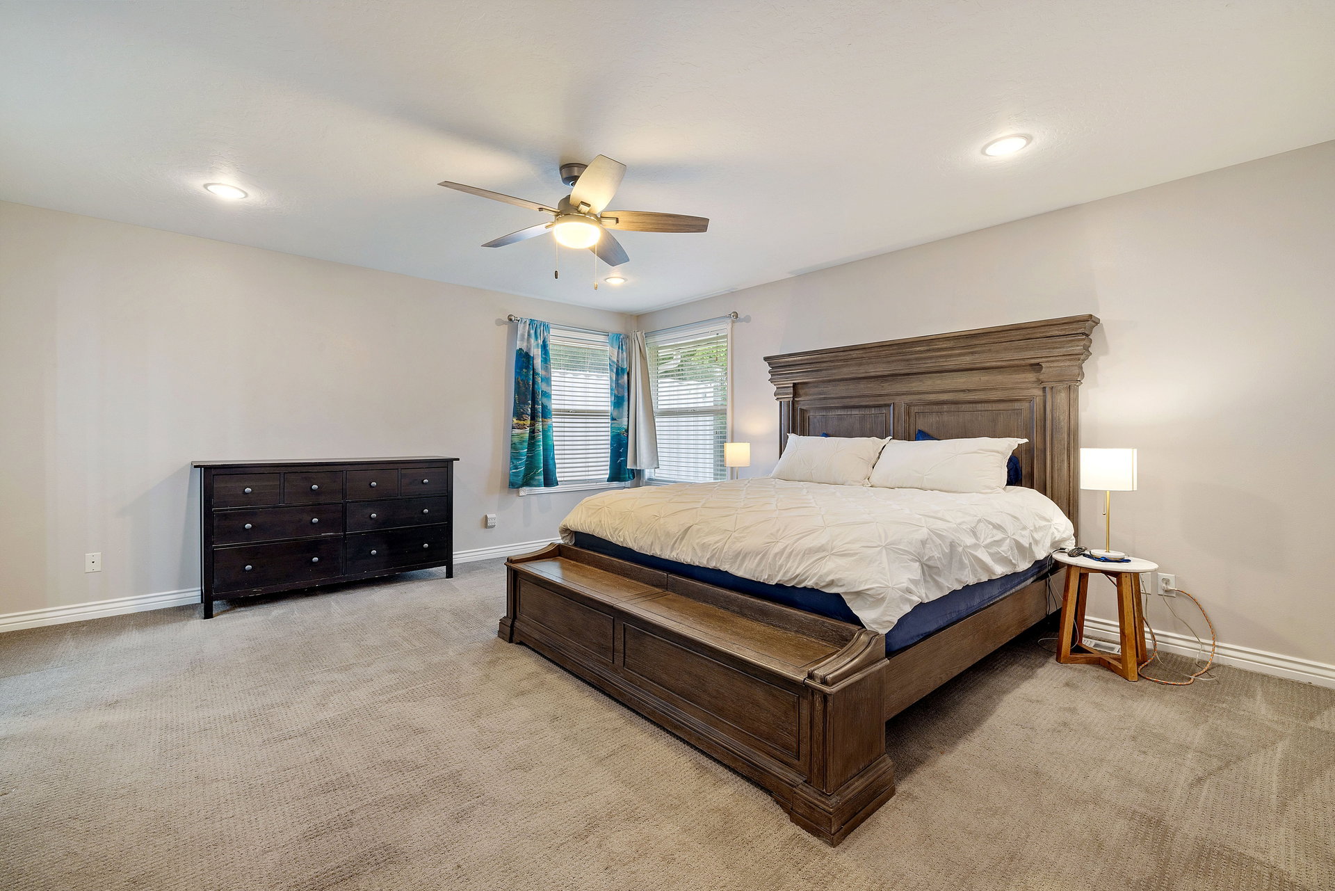 Spacious bedroom featuring light-colored walls, recessed lighting, and a ceiling fan