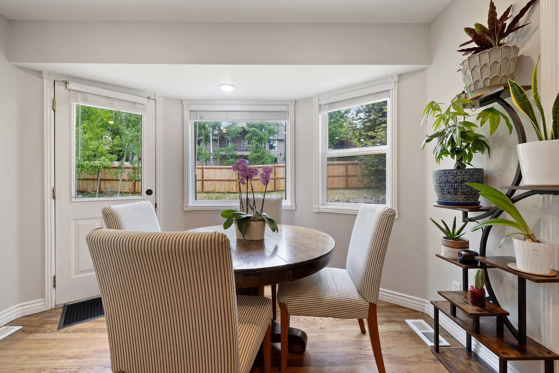Light-filled dining area featuring wood-finish flooring, a bay window configuration, and a paneled rear door with an integrated window