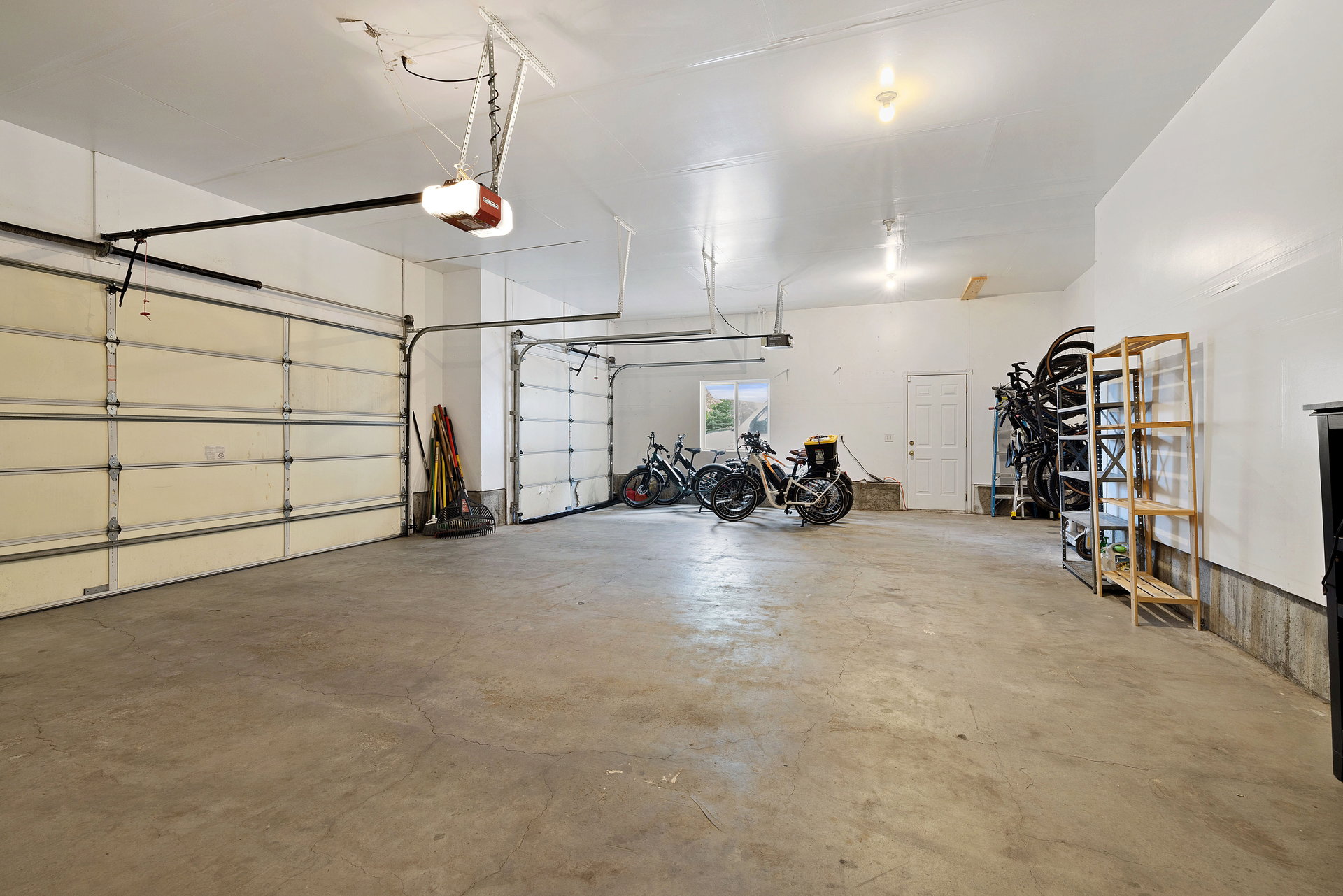 Spacious garage featuring two overhead doors, a concrete floor, and white painted walls