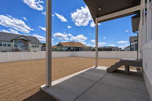 Expansive backyard featuring a newly seeded lawn, full vinyl privacy fencing, and a concrete patio with an overhead structural awning