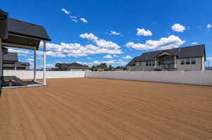 Expansive backyard featuring a prepared earth surface, a white vinyl privacy fence, and a covered patio with direct access to the interior