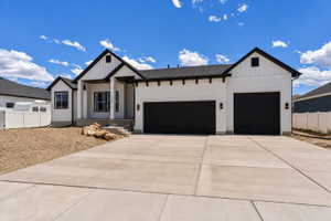 Contemporary-style residence featuring a white exterior with black trim, a two-car garage with black doors, a covered entry porch supported by white columns, and a concrete driveway