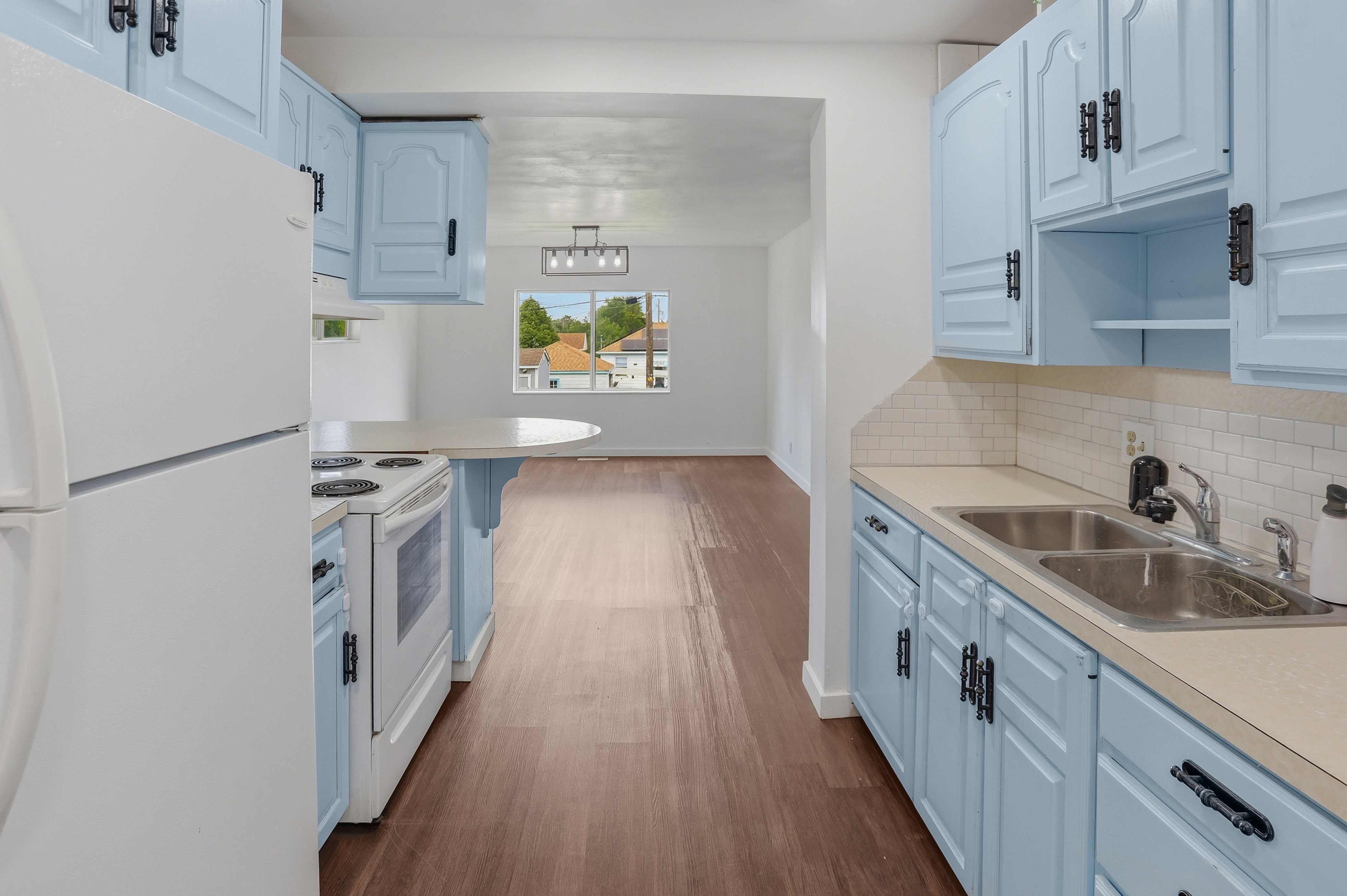 Kitchen featuring light blue cabinetry with dark hardware, white subway tile backsplash, and a double basin stainless steel sink