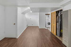 Open floor plan featuring wood-finish flooring, white walls, and a recessed laundry area with a visible washer