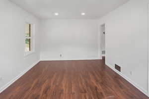 Spacious room featuring rich wood-finish flooring, crisp white walls, and recessed lighting
