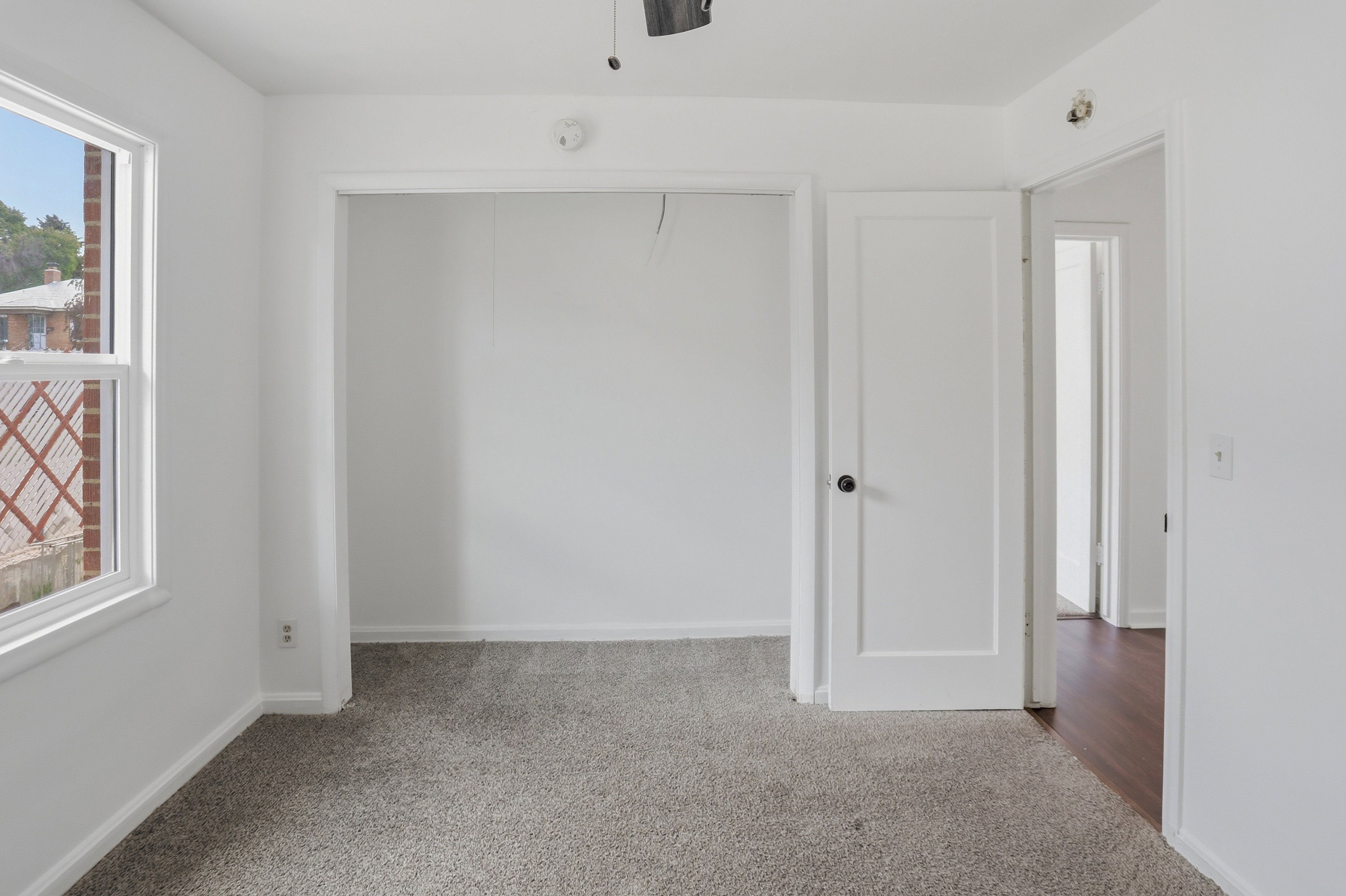 Room featuring neutral-toned carpeting, white walls, and a window with white trim