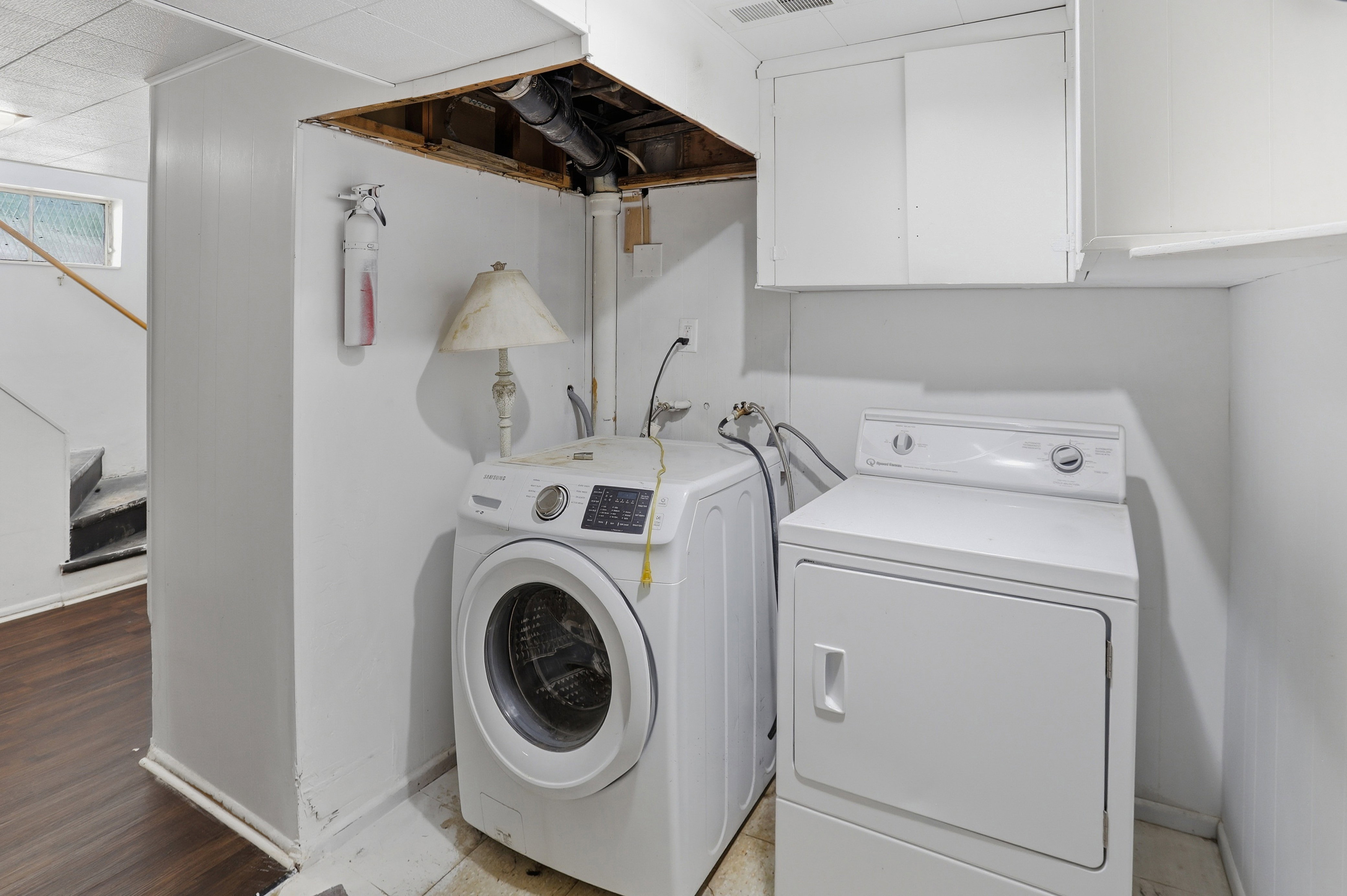 Dedicated laundry area featuring a washer and dryer, white cabinetry, and wood-finish flooring extending into the adjacent space